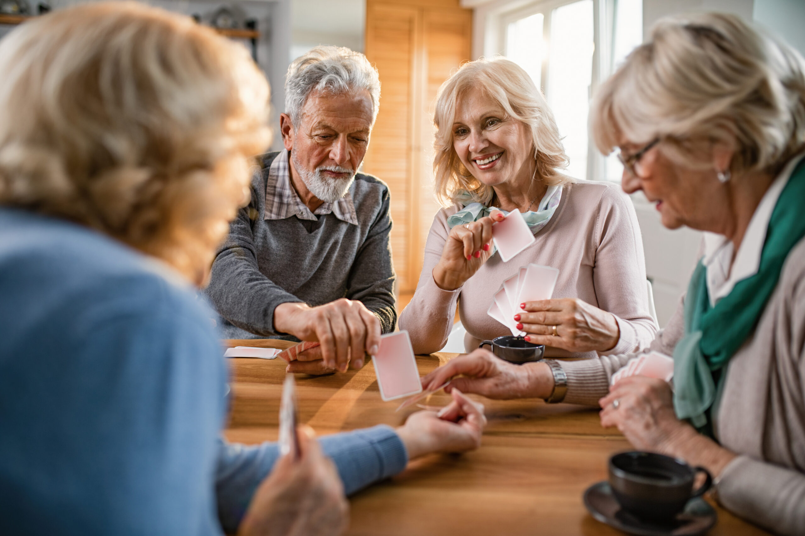 Small group of mature friends enjoying while playing cards at ho